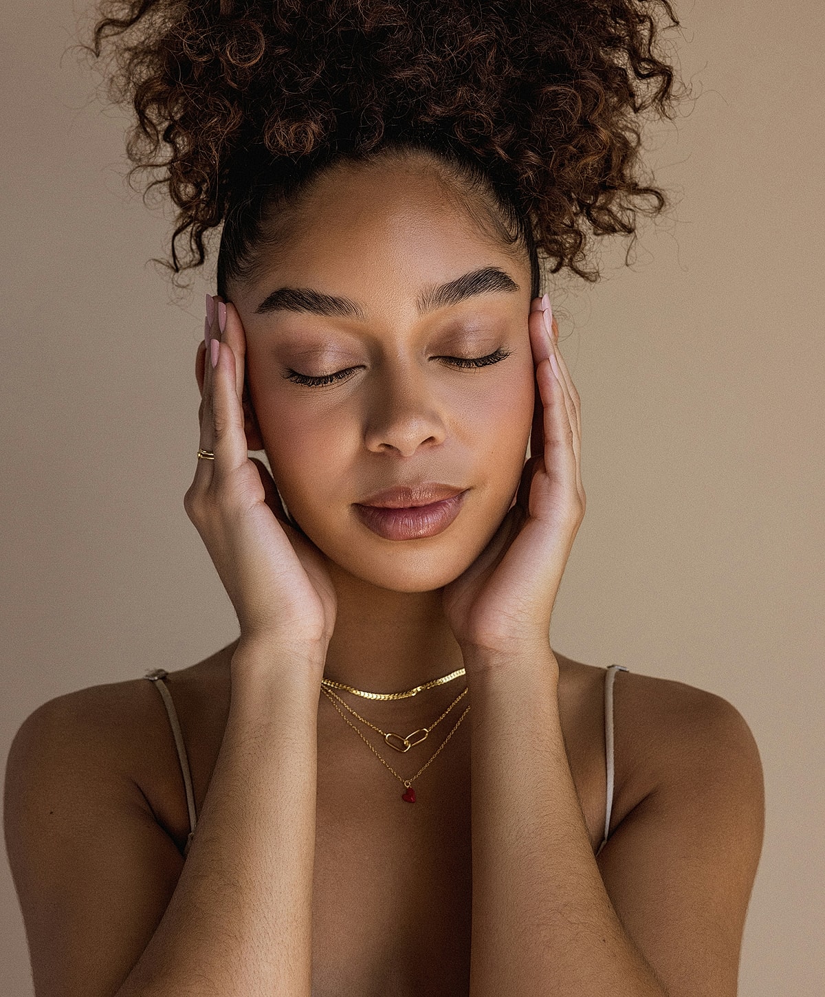 Woman with closed eyes, holding her face gently.