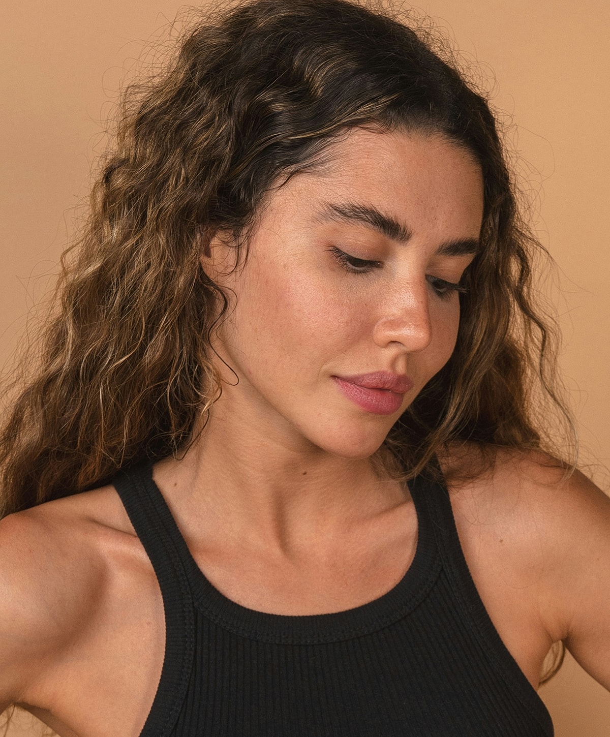 Woman with wavy hair against neutral background.