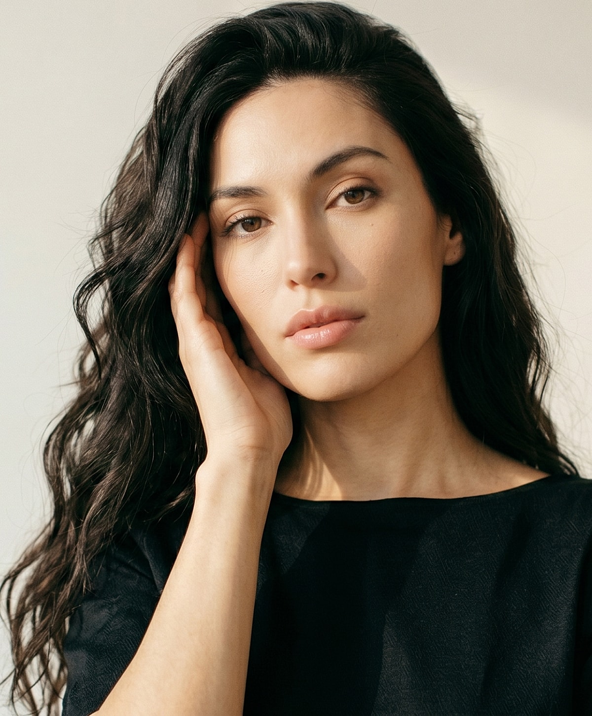Woman with long, wavy hair in neutral top.