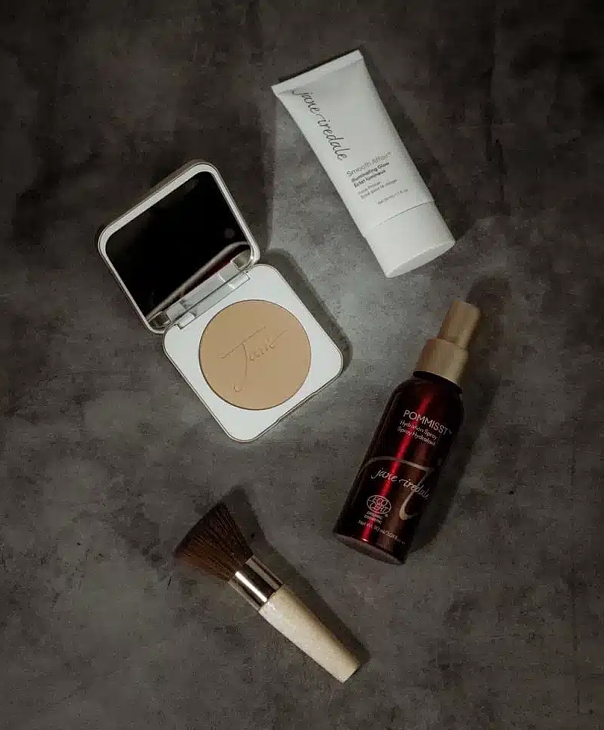 Makeup products arranged on a dark surface.