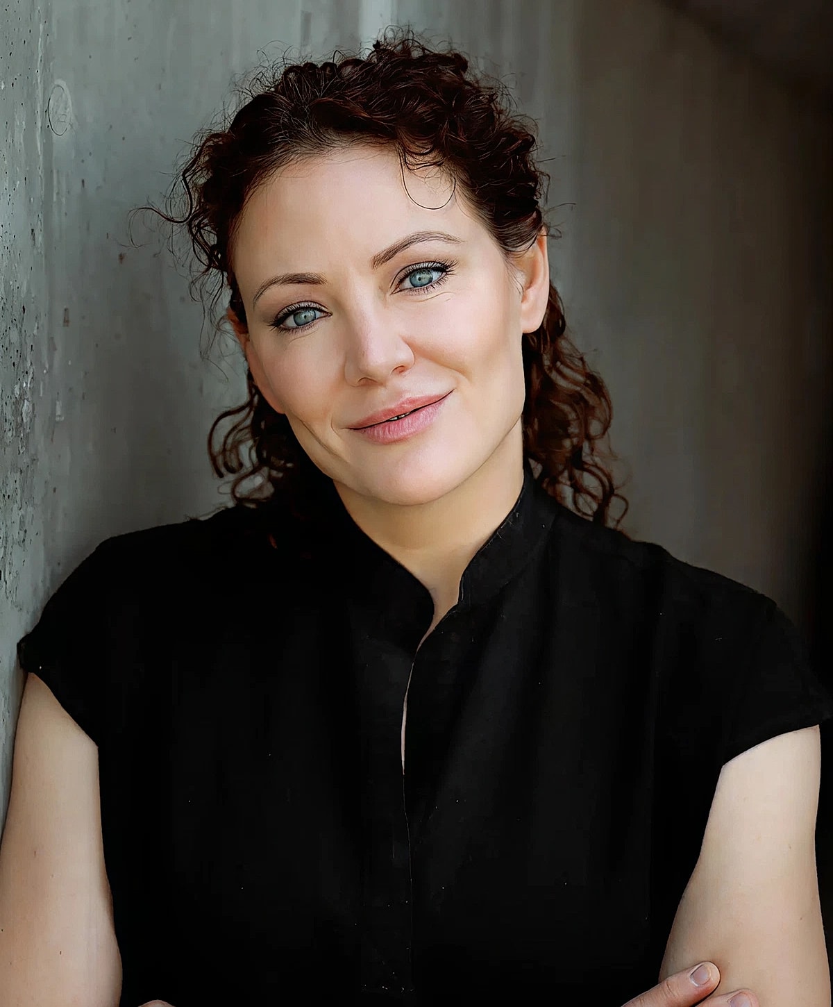 Smiling woman with curly hair in casual attire.