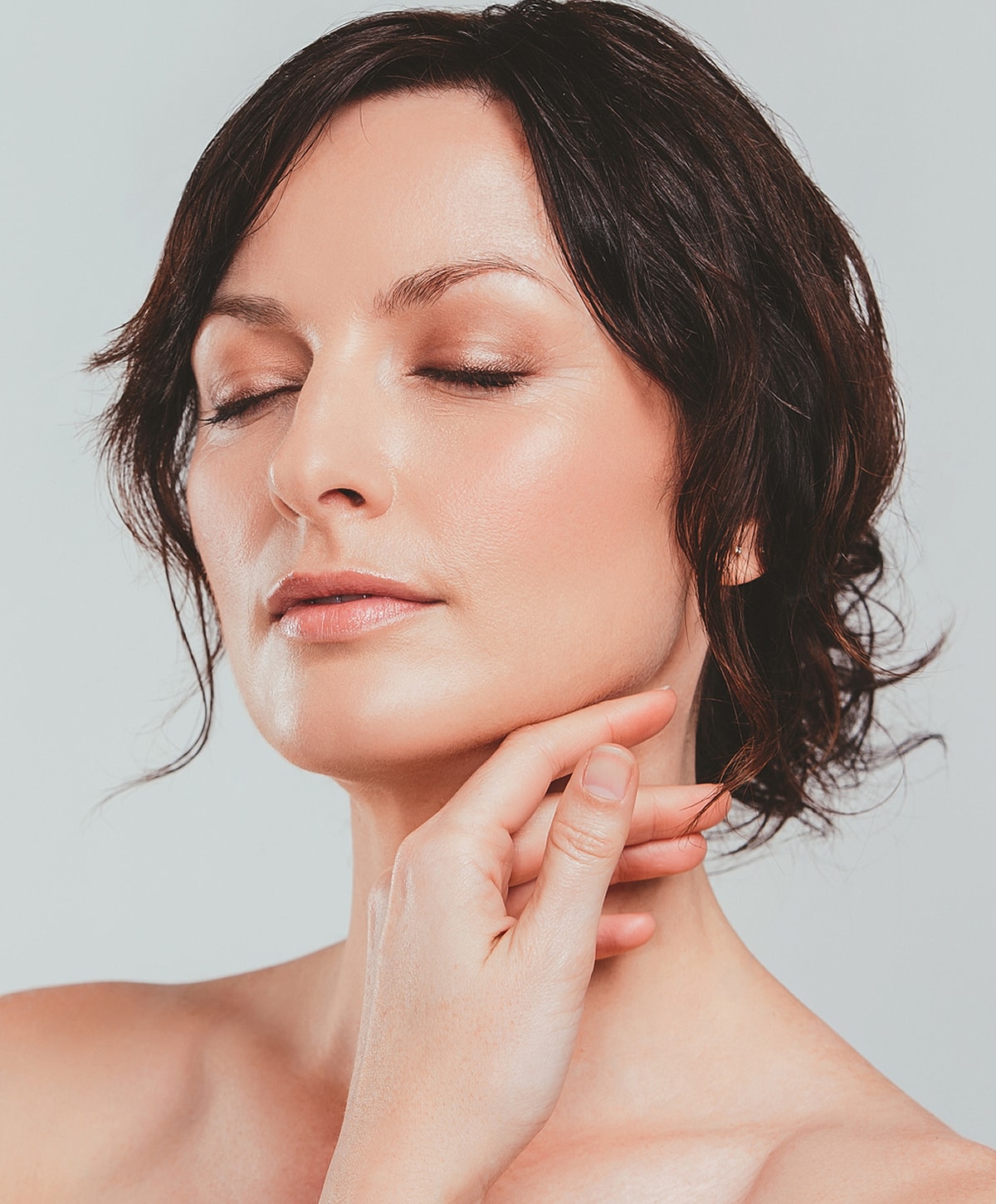 Woman with closed eyes, soft expression and hand.