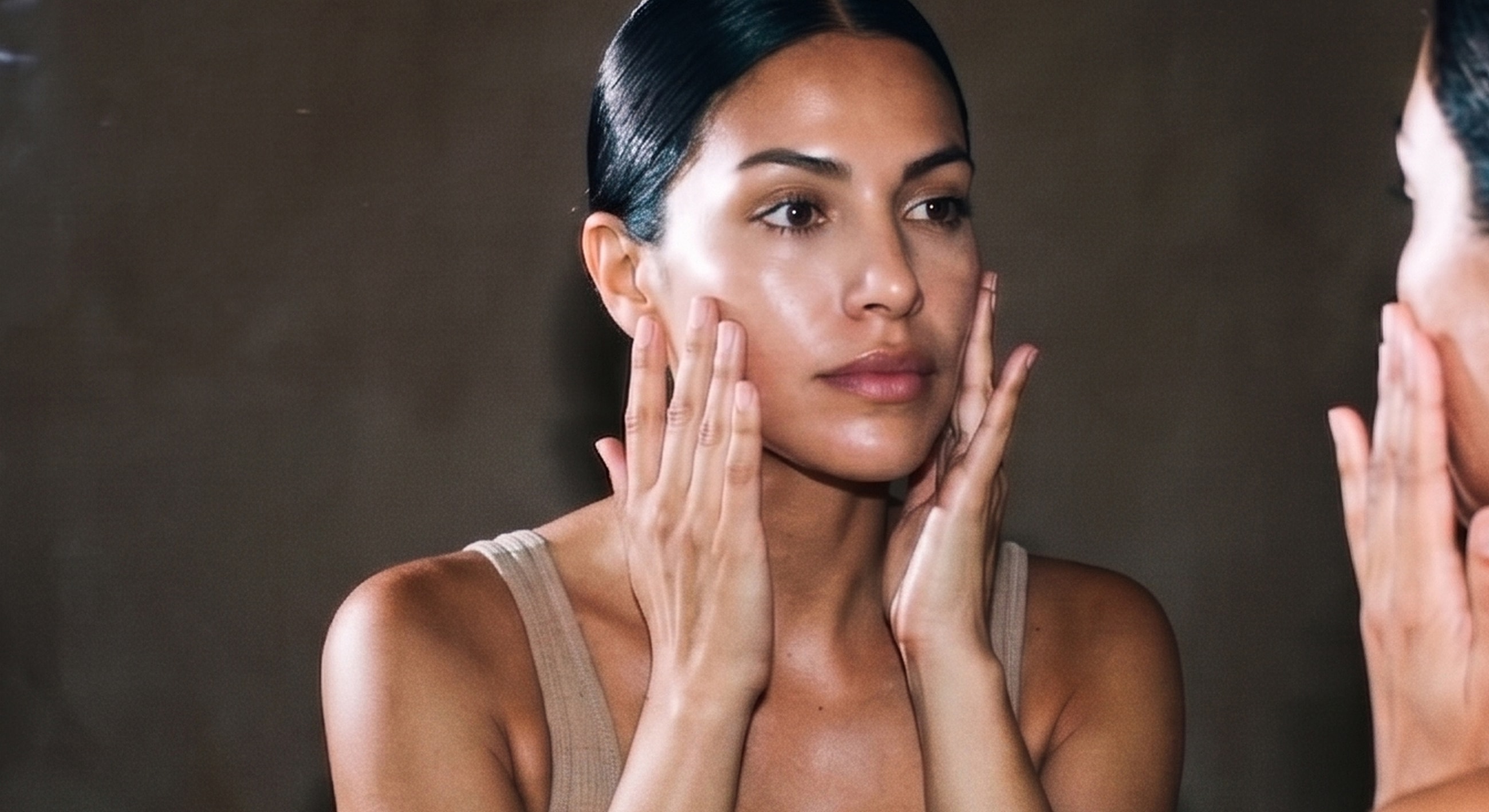 Woman applying skincare in mirror reflection.